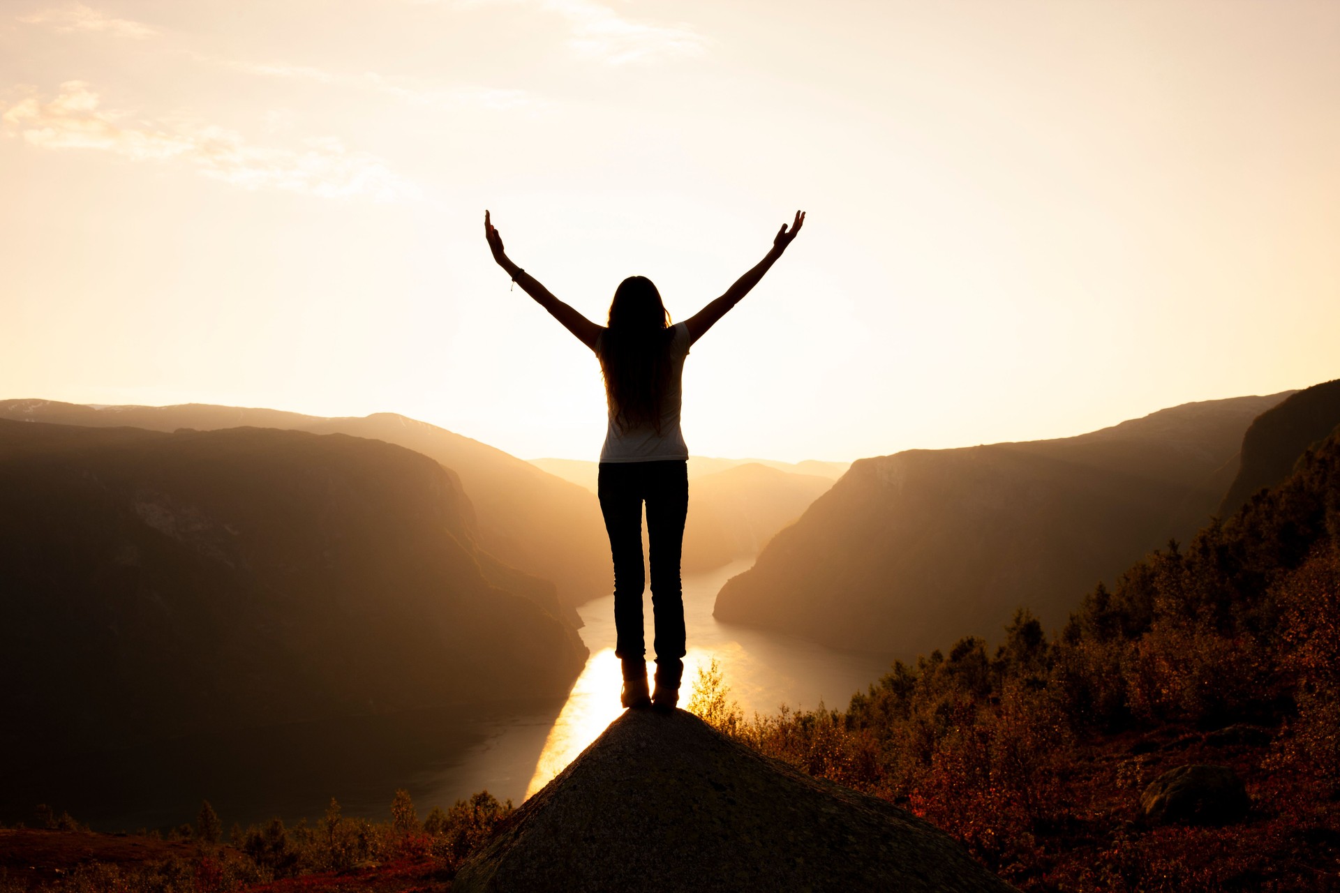 Silhouette of a woman with arms outstretched at sunrise