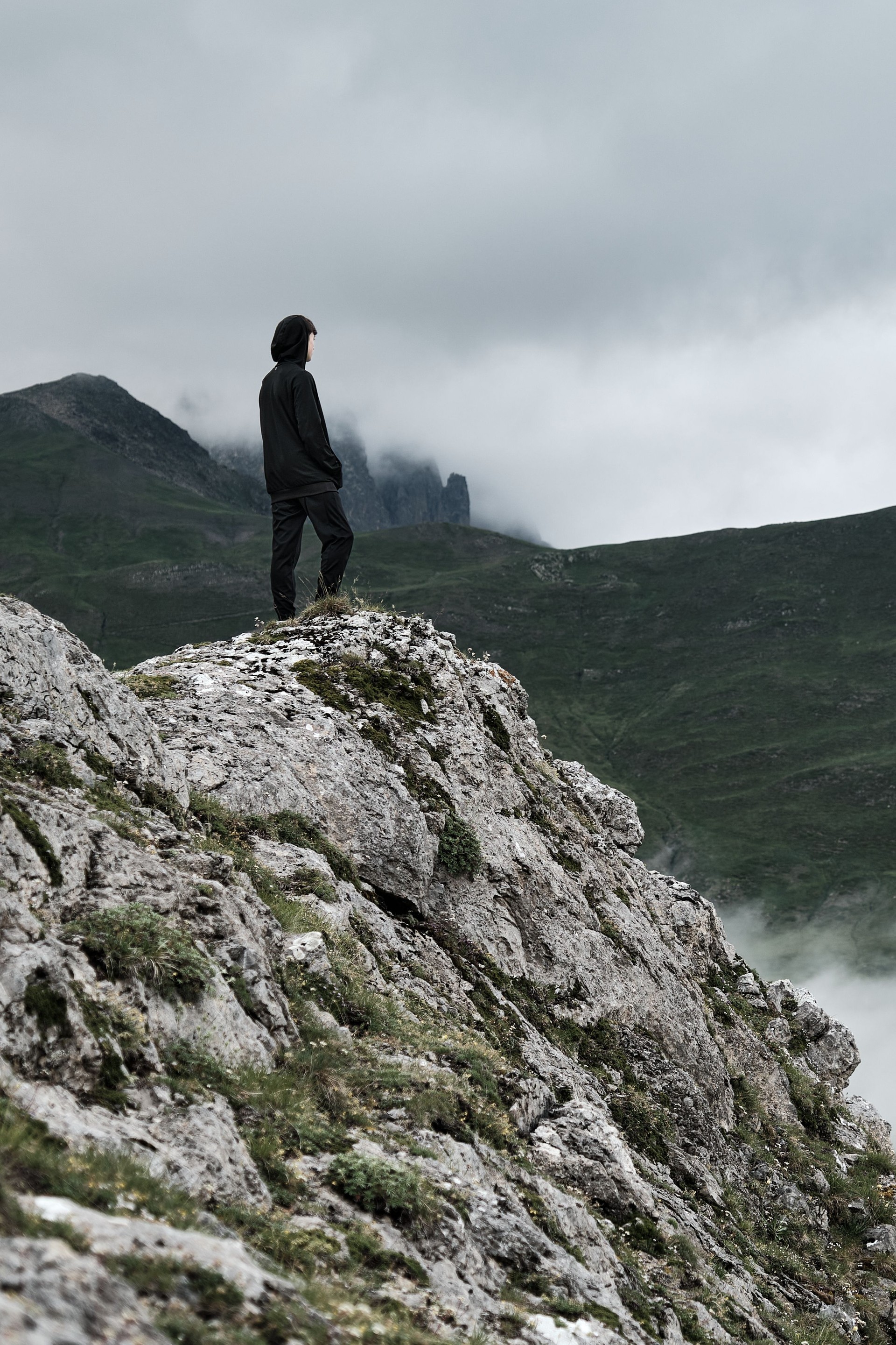 Unrecognizable teenager wearing a hoodie and dark clothing in nature